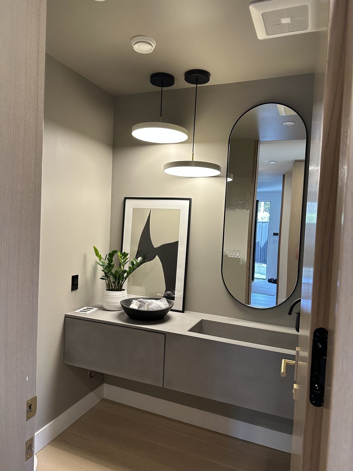 Bathroom vanity with oval mirror and pendant lighting