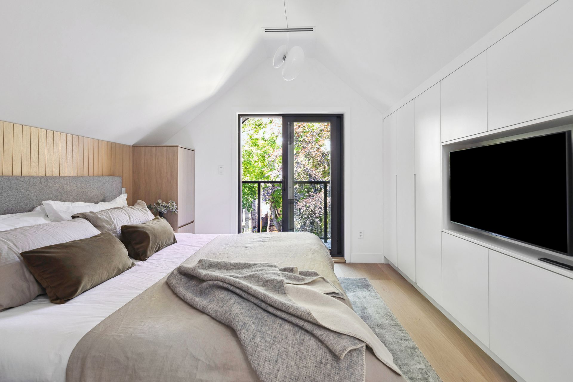 Primary bedroom with vaulted ceiling and private balcony