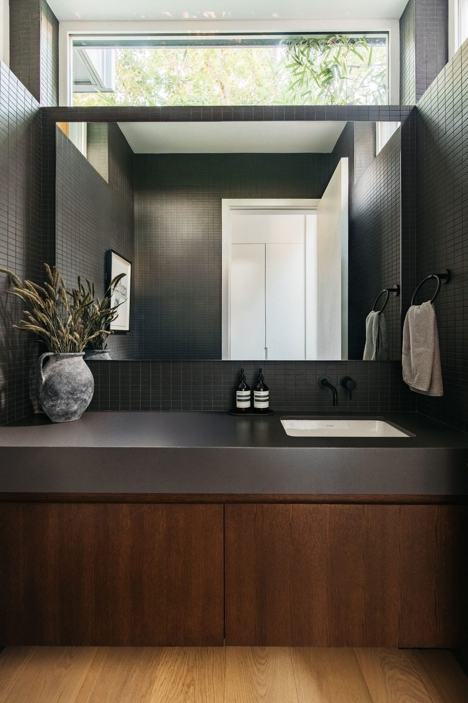 Powder room with dark accent wall and floating wood vanity